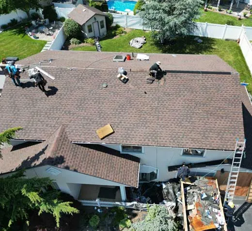 Inspecting asphalt shingles for roof damage from heat and UV exposure on a Long Island home